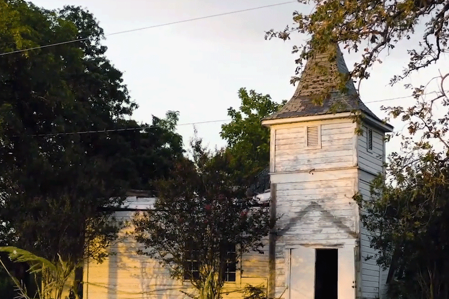 old white church with a green grassy lawn and many trees